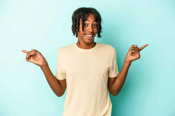 Joven Afroamericano Aislado Sobre Fondo Azul Apuntando Diferentes Espacios Copia —  Fotos de Stock