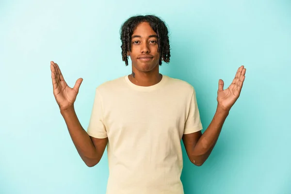 若いアフリカ系アメリカ人の男は青い背景に何かを抱いている — ストック写真