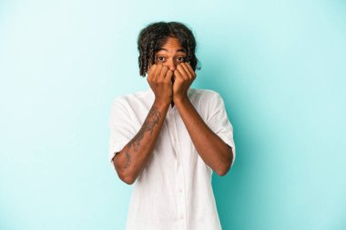 Genç Afrikalı Amerikalı bir adam mavi arka planda izole edilmiş tırnak yiyor, gergin ve çok endişeli..