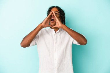 Genç Afrikalı Amerikalı adam mavi arka planda izole edilmiş ve heyecanlı bir şekilde bağırıyor..