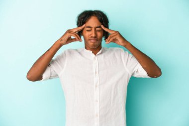 Genç Afrikalı Amerikalı bir adam mavi arka planda izole edilmiş vazifesine odaklanmış, işaret parmaklarını işaret ediyor..