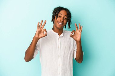 Genç Afrikalı Amerikalı adam mavi arka planda izole edilmiş neşeli ve kendinden emin..
