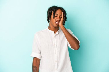 Genç Afrikalı Amerikalı adam mavi arka planda izole edilmiş. Yorgun ve uykulu. Elini başının üstünde tutuyor..