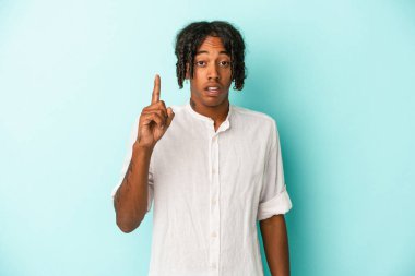 Genç Afrikalı Amerikalı bir adam mavi arka planda izole edilmiş. Bir fikri, ilham verici bir konsepti var..