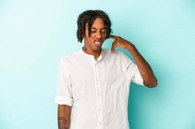 Genç Afrikalı Amerikalı adam mavi arka planda izole edilmiş kulakları elleriyle kapatıyor..