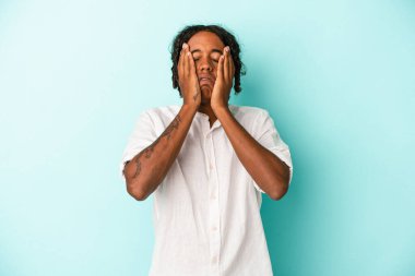 Genç Afro-Amerikalı adam mavi arka planda yalnız başına sızlanıyor ve ağlıyordu..