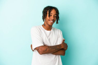 Genç Afrikalı Amerikalı adam mavi arka planda izole edilmiş gülüyor ve eğleniyor..