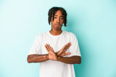 Genç Afrikalı Amerikalı adam mavi arka planda izole edilmiş bir şekilde inkar jesti yapıyor.