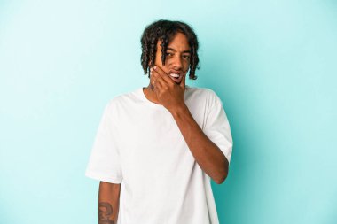 Genç Afrikalı Amerikalı bir adam mavi arka planda izole edilmiş güçlü bir diş ağrısı ve azı dişi ağrısı var..
