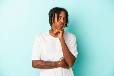 Genç Afro-Amerikalı bir adam mavi arka planda izole edilmiş bir şekilde bir strateji planlıyor, bir işin nasıl olacağını düşünüyor..