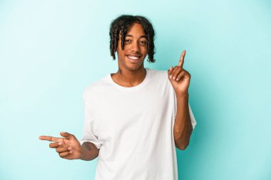 Genç Afro-Amerikan adam mavi arka planda izole edilmiş farklı kopya alanlarını işaret ederek, onlardan birini seçiyor, parmaklarıyla gösteriyor.