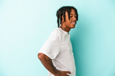 Genç Afrikalı Amerikalı adam mavi arka planda izole edilmiş sırt ağrısı çekiyor..