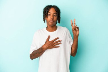 Genç Afrikalı Amerikalı adam mavi arka planda izole edilmiş bir şekilde yemin ediyor, elini göğsüne koyuyor..