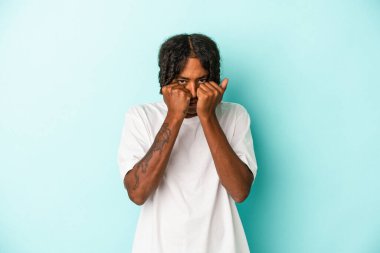 Genç Afrikalı Amerikalı bir adam mavi arka planda izole edilmiş. Bir tartışma yüzünden yumruk, öfke ve kavga atıyor..