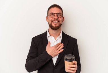 Beyaz arka planda izole edilmiş kahveyi alıp götüren beyaz iş adamı kahkahalarla gülüyor ve elini göğsünde tutuyor..