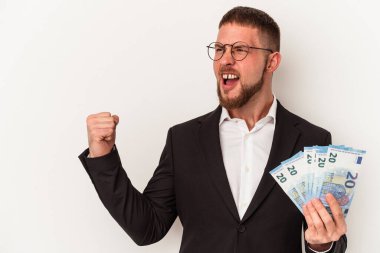 Beyaz arka planda izole edilmiş banknotlar tutan genç beyaz adam zaferden sonra yumruğunu kaldırıyor, kazanan konsept..
