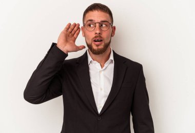 Beyaz arka planda izole edilmiş genç beyaz bir adam bir dedikoduyu dinlemeye çalışıyor..