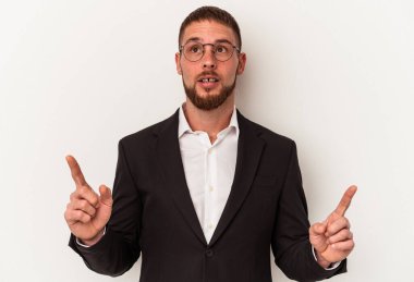 Beyaz arka planda izole edilmiş genç beyaz bir adam ağzı açık bir şekilde üst tarafı işaret ediyor..