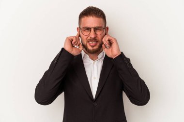 Beyaz arka planda izole edilmiş genç bir beyaz adam kulaklarını elleriyle kapatıyor..