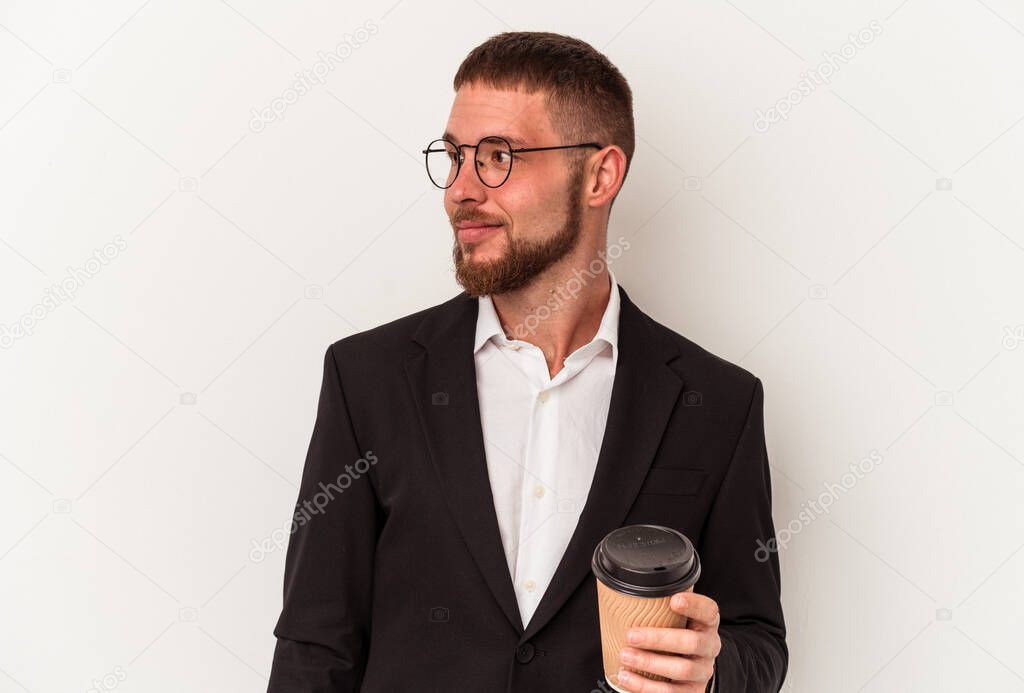 Young business caucasian man holding take away coffee isolated on white background looks aside smiling, cheerful and pleasant.