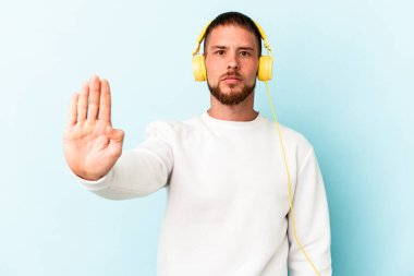 Mavi arka planda izole edilmiş müzik dinleyen beyaz bir adam elini uzatmış, dur işareti göstererek seni engelliyor..