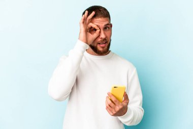 Elinde cep telefonu olan beyaz bir adam mavi arka planda izole edilmiş..