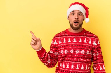 Sarı arka planda izole edilmiş genç beyaz adam Noel 'i kutluyor.