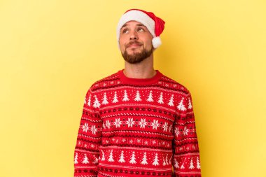 Genç beyaz adam, sarı arka planda izole edilmiş bir şekilde Noel 'i kutluyor. Amaçlarına ve amaçlarına ulaşma hayali kuruyor.