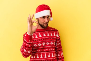 Genç beyaz adam Noel 'i kutluyor. Sarı arka planda izole edilmiş. Neşeli ve kendinden emin..