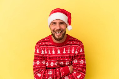 Genç beyaz adam Noel 'i kutluyor. Sarı arka planda izole edilmiş. Gülüyor ve eğleniyor..