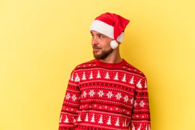 Sarı arka planda izole edilmiş bir şekilde Noel 'i kutlayan genç beyaz adam gülümsüyor ve keyifli görünüyor..