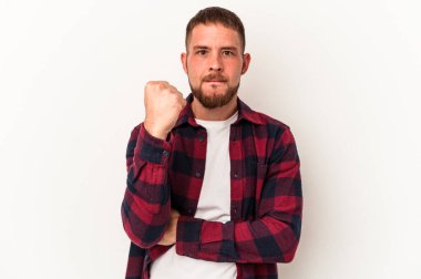 Diastemalı genç beyaz adam beyaz arka planda izole edilmiş kameraya yumruk gösteriyor, agresif yüz ifadesi var..