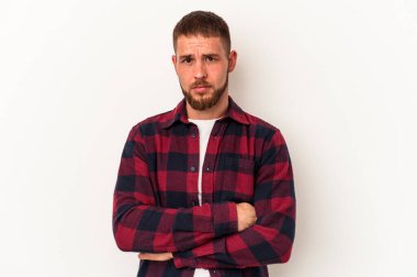 Beyaz arka planda izole edilmiş beyaz tenli genç beyaz adam alaycı bir ifadeyle kameraya bakıyor..