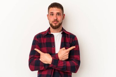 Diastemalı genç beyaz arka plan noktalarında izole edilmiş beyaz bir adam iki seçenek arasında seçim yapmaya çalışıyor..