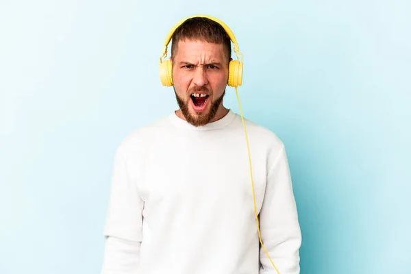 Ung Kaukasisk Man Lyssnar Musik Isolerad Blå Bakgrund Skriker Mycket — Stockfoto