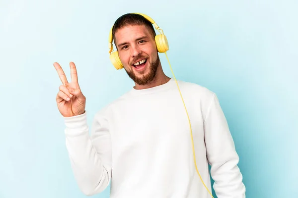 Young Caucasian Man Listening Music Isolated Blue Background Joyful Carefree — Stock Photo, Image