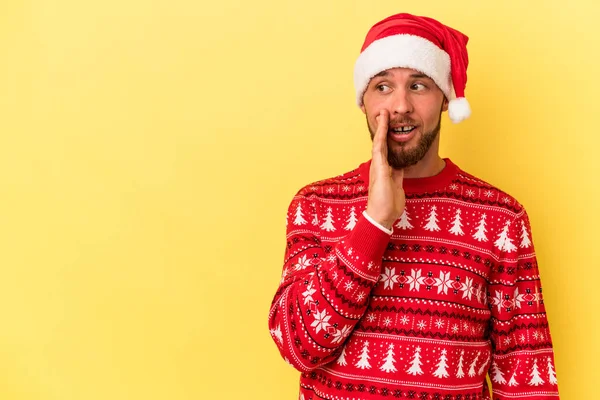 Sarı arka planda izole edilmiş bir şekilde Noel 'i kutlayan genç beyaz adam gizli bir sıcak fren haberi veriyor ve yan bakıyor.