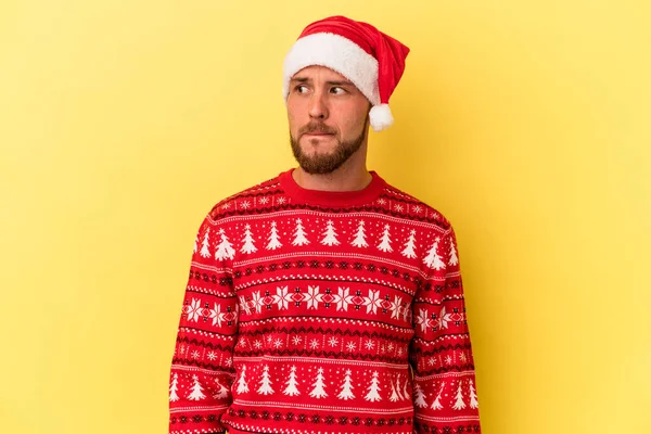 Kafkasyalı genç adam, Noel 'i sarı arka planda yalnız kutluyor. Kafası karışık ve kendinden emin değil..