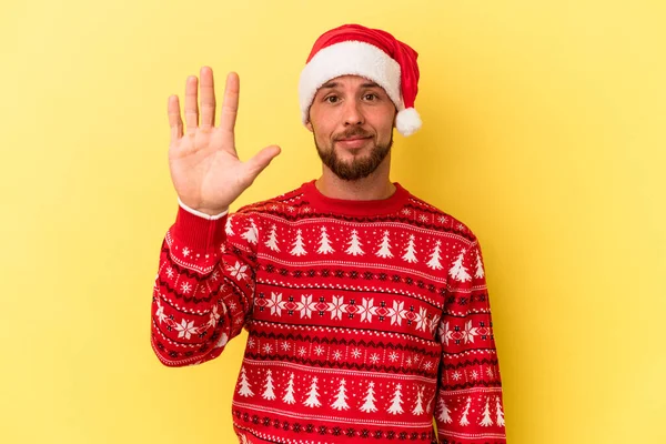 若いですCaucasian男祝いますクリスマス絶縁上の黄色の背景笑顔陽気なショー番号5とともに指 — ストック写真