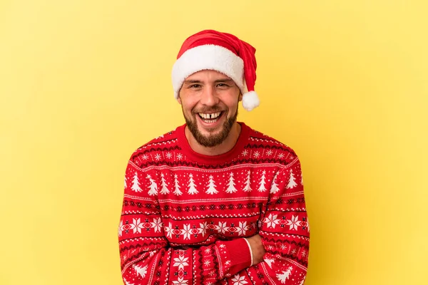 Genç beyaz adam Noel 'i kutluyor. Sarı arka planda izole edilmiş. Gülüyor ve eğleniyor..