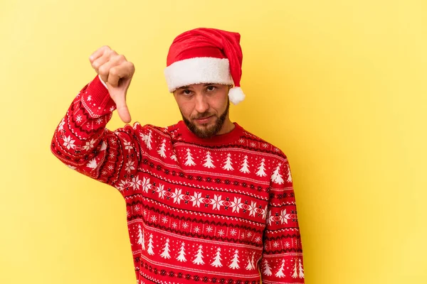 Sarı arka planda izole edilmiş, hoşlanmadığı bir jest gösteren genç, beyaz bir adam Noel 'i kutluyor. Anlaşmazlık konsepti.