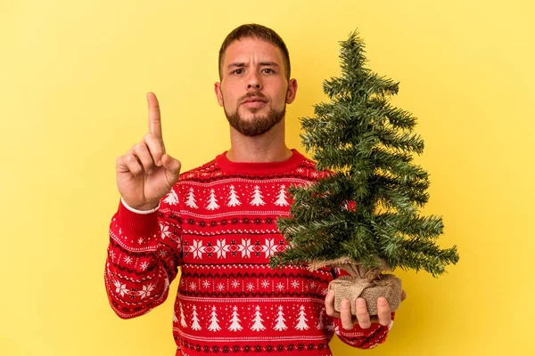 Młody Biały Człowiek Kupuje Mały Drzewo Boże Narodzenie Odizolowany Żółtym — Zdjęcie stockowe