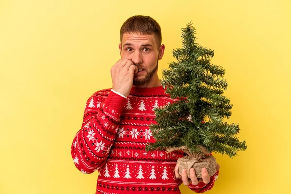 Młody Biały Mężczyzna Kupuje Choinkę Boże Narodzenie Odizolowany Żółtym Tle — Zdjęcie stockowe