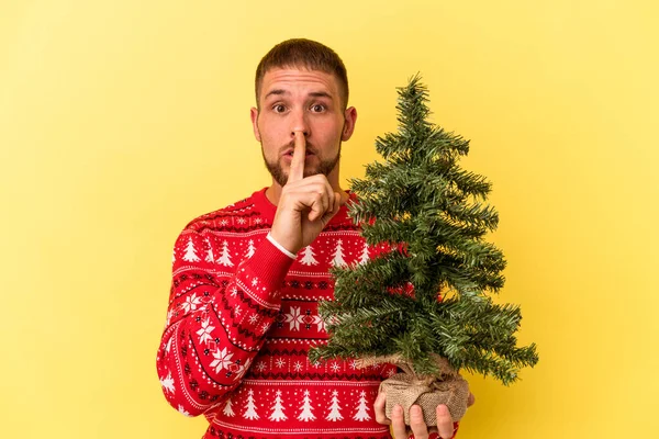 Junger Kaukasischer Mann Kauft Weihnachtsbaum Isoliert Auf Gelbem Hintergrund Und — Stockfoto