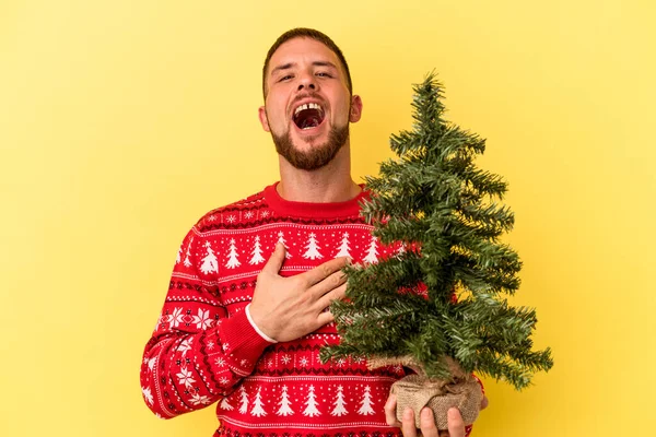 Młody Biały Człowiek Kupuje Mały Drzewo Boże Narodzenie Odizolowany Żółtym — Zdjęcie stockowe