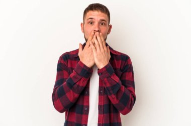 Beyaz arka planda izole edilmiş beyaz tenli genç beyaz adam şok olmuş, ağzı ellerle kaplanmış, yeni bir şey keşfetmeye hevesli..