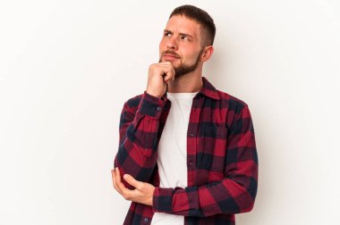 Diastemalı genç beyaz adam beyaz arka planda izole edilmiş düşünüyor ve yukarı bakıyor, yansıtıyor, düşünüyor, hayal kuruyor..