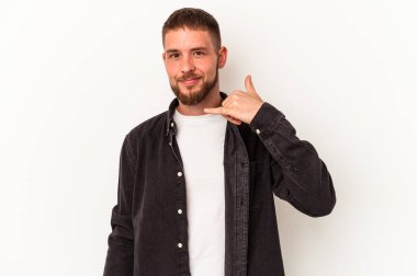 Beyaz arka planda izole edilmiş diyastemalı genç beyaz adam parmaklarıyla bir cep telefonu hareketi gösteriyor..