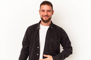 Beyaz arka planda izole edilmiş beyaz tenli genç beyaz adam karnına dokunuyor, nazikçe gülümsüyor, yemek yiyor ve tatmin oluyor..