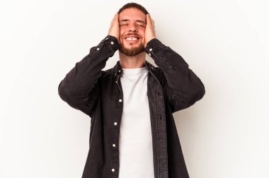 Beyaz arka planda izole edilmiş beyaz tenli genç beyaz adam ellerini başının üstünde tutarak neşeyle gülüyor. Mutluluk kavramı.